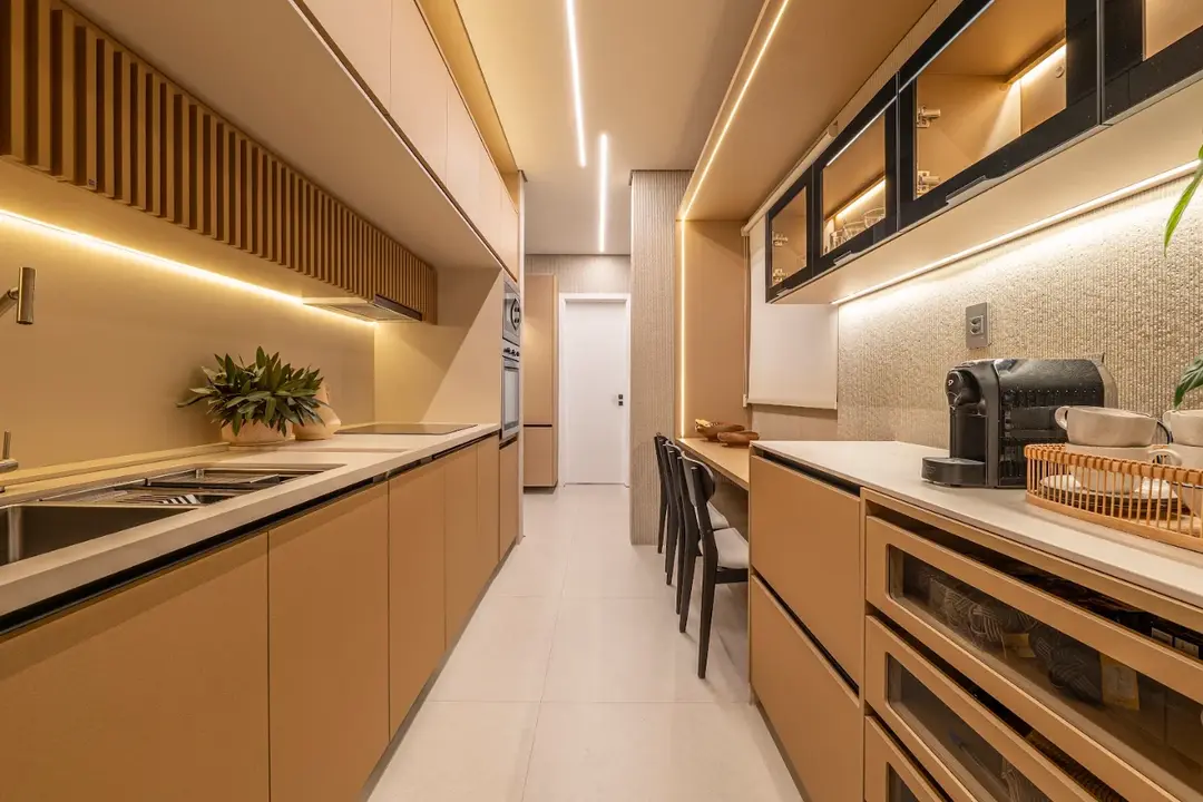 Cozinha corredor com marcenaria em tom terracota, iluminação linear em LED e bancada de trabalho integrada.